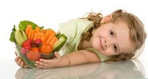 bambina stradaiata per terra con in mano un contenitore con frutta e verdura