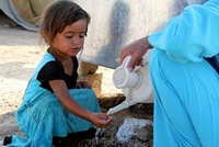 una bambina nell'atto di prendere dell'acqua