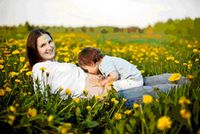Una mamma in un prato fiorito con in braccio un bambino